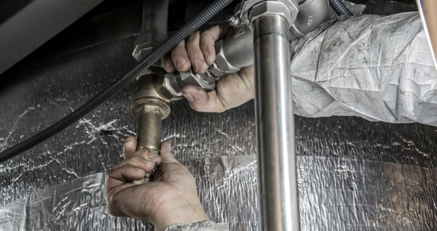 Plombier réparant une rupture de canalisation, tuyau éclaté avec fuite d'eau